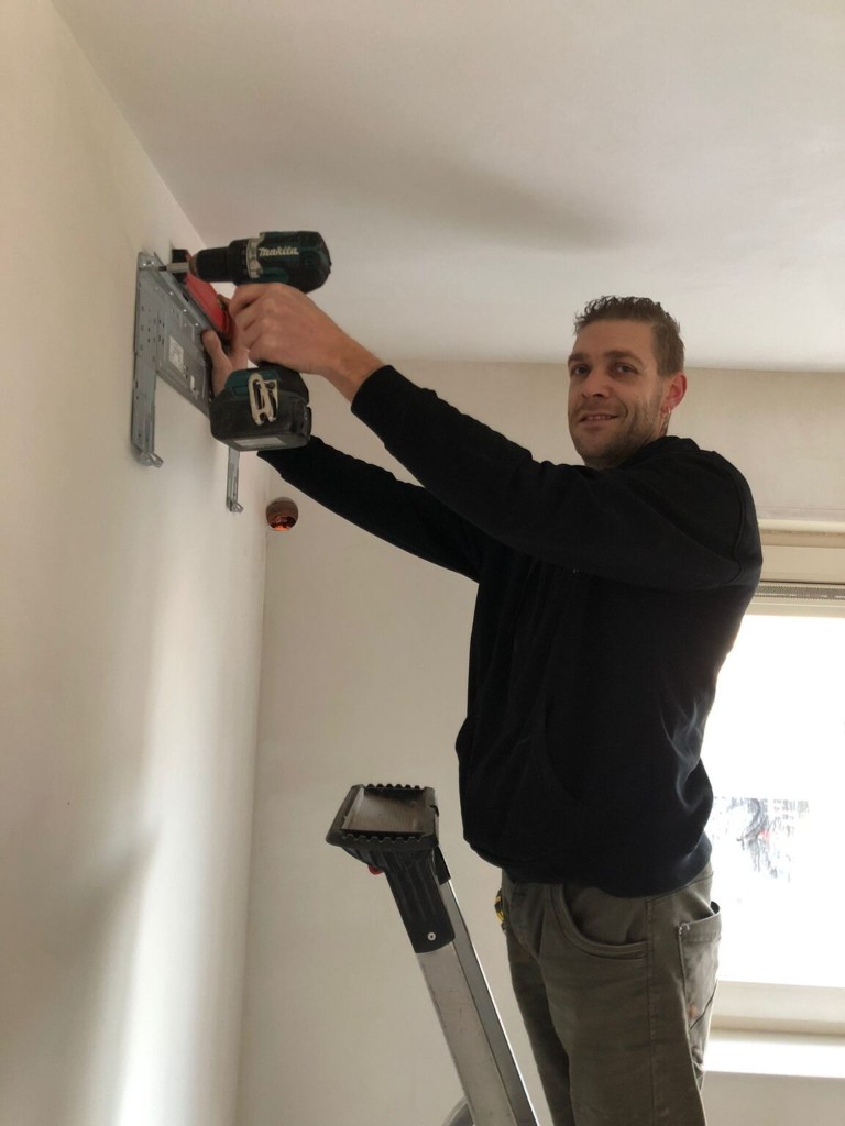 Monteur bevestigt de wandbeugel voor een binnendeel van de airconditioning